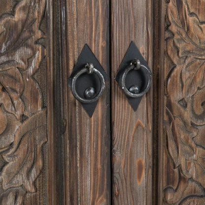 Wooden door with intricate carvings and metal ring handles.