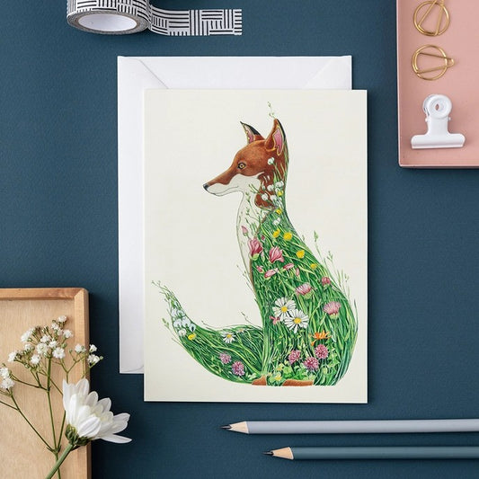 Card with fox painted using flowers and grass surrounded by stationery.