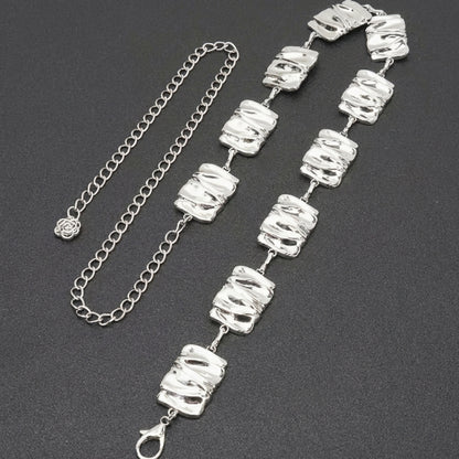 Silver chain and bracelet with textured square links on a dark background.