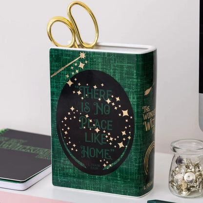 Green book-shaped container with scissors, quote: "There is no place like home."