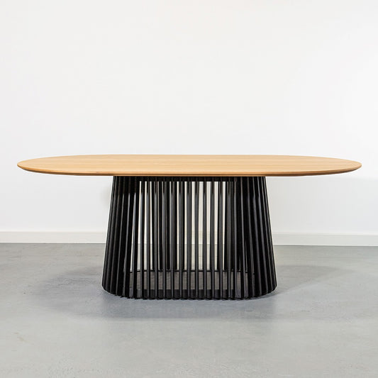 Oval wooden table with a black ribbed base.
