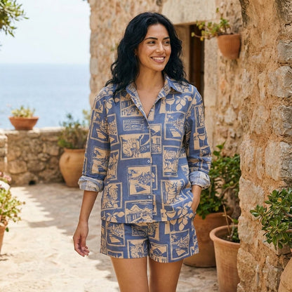 Woman in a patterned outfit strolling by a stone wall with ocean view.