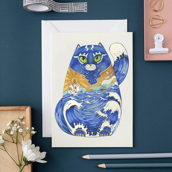 Artistic cat with ocean waves, lighthouse inside a card with stationary around.