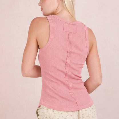 Woman in pink ribbed tank top with decorative back seam, turned slightly sideways.