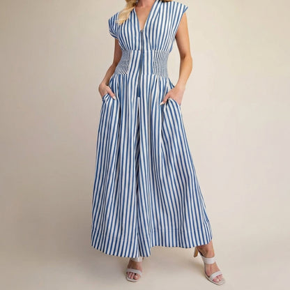 Woman in a blue and white striped maxi dress, hands in pockets.