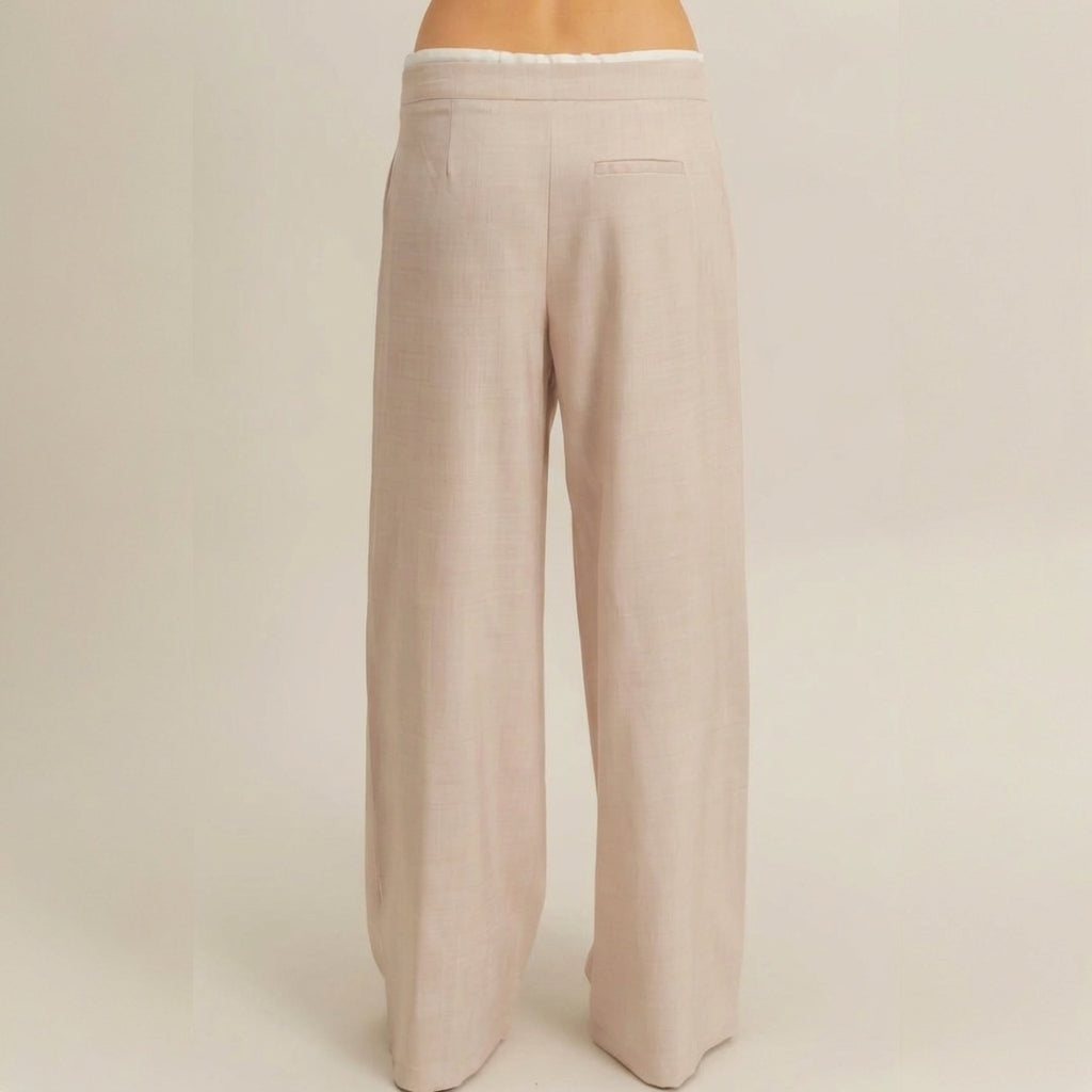 Back view of beige, wide-leg trousers with a single back pocket.
