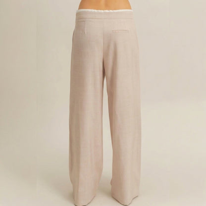 Back view of beige, wide-leg trousers with a single back pocket.