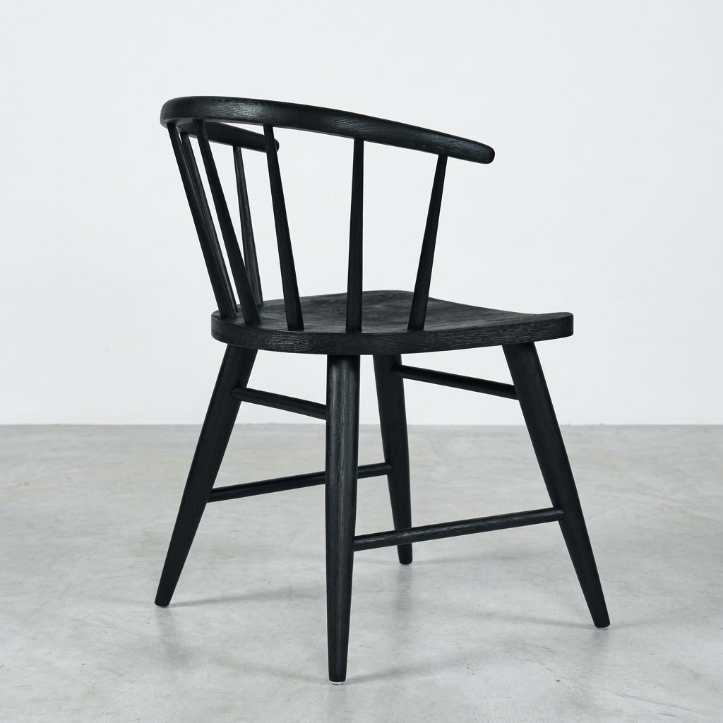 Black wooden chair with a curved back and spindles, side view.
