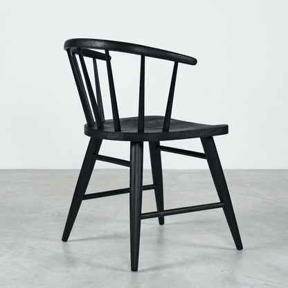 Black wooden chair with a curved back and spindles, side view.