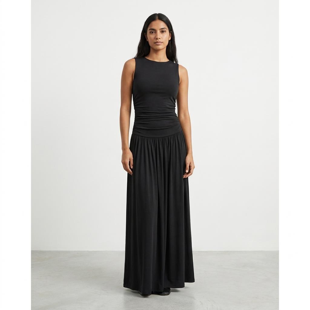 Woman in a sleeveless black dress stands against a plain white background.