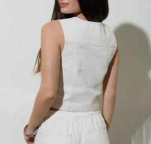 Person in white co-ord outfit stands facing away from the camera.