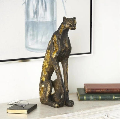 Bronze and gold feline sculpture on mantel by books and painting.