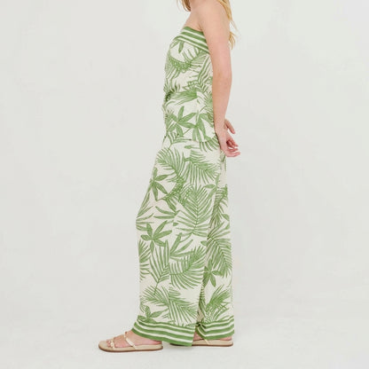Person in a strapless, leafy-patterned jumpsuit and sandals, side view.
