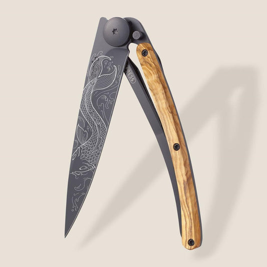 Folding knife with engraved blade and wooden handle on beige background.