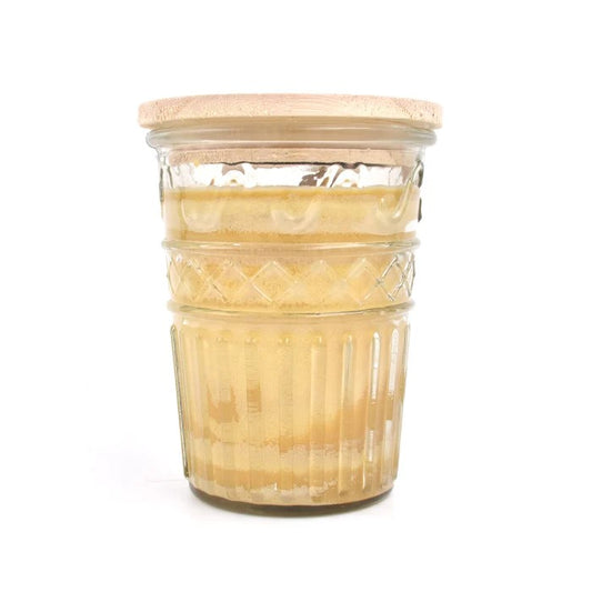 Glass jar with ridged pattern, filled with creamy substance.