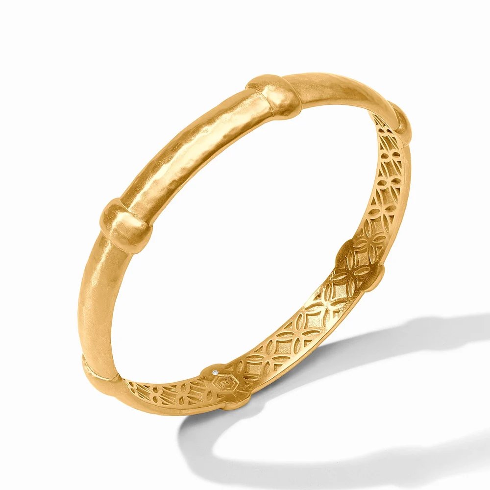 A gold bangle bracelet with ornate filigree detailing, photographed against a white background.