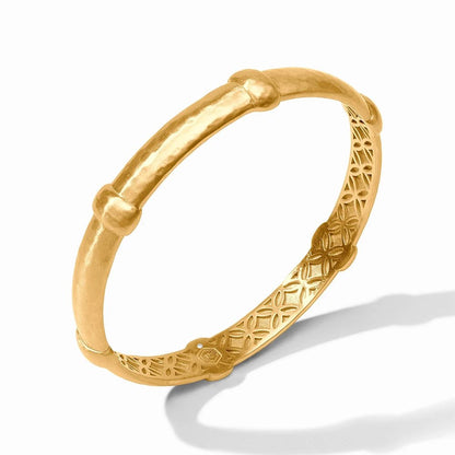 A gold bangle bracelet with ornate filigree detailing, photographed against a white background.