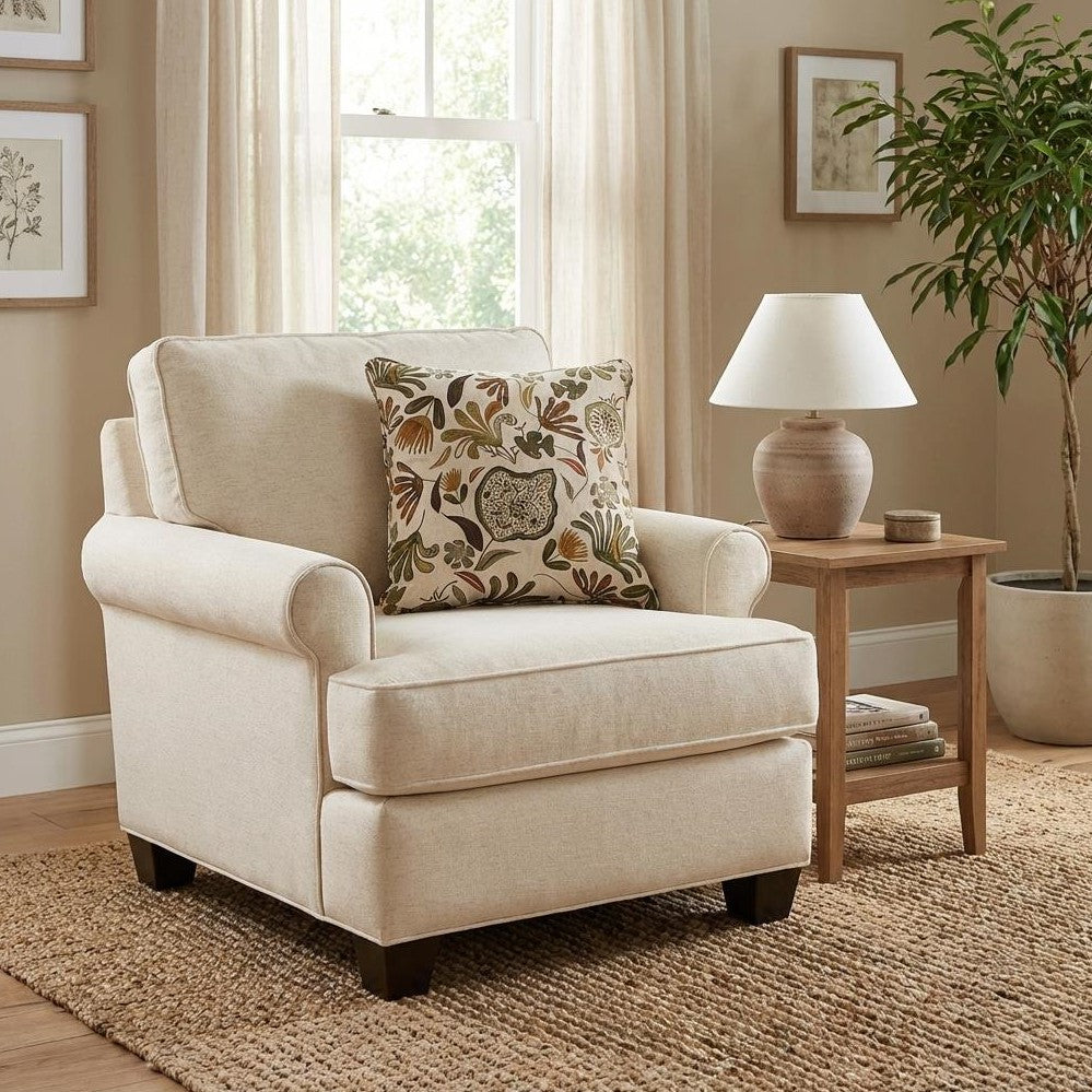 Cozy beige armchair with a floral cushion in a sunny room with lamp, table, and plant.