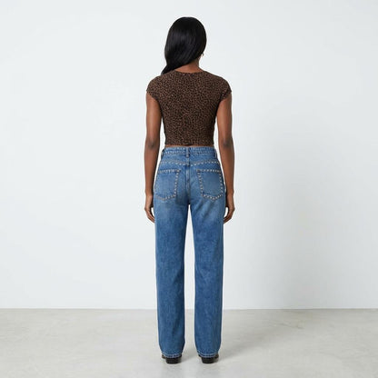 Woman in leopard top and jeans, standing back to camera.