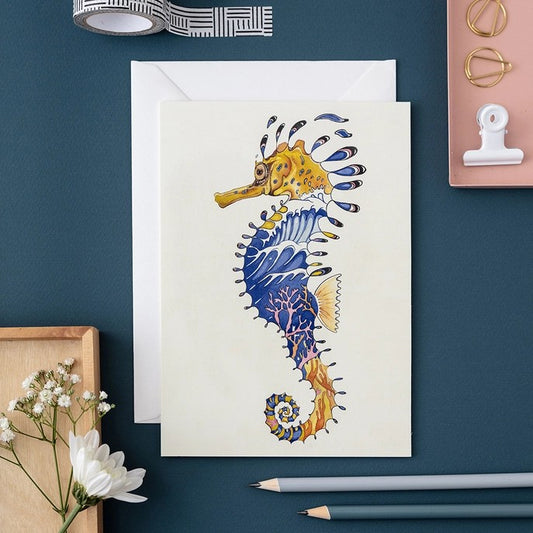 Colorful seahorse illustration on a greeting card with stationery and flowers.