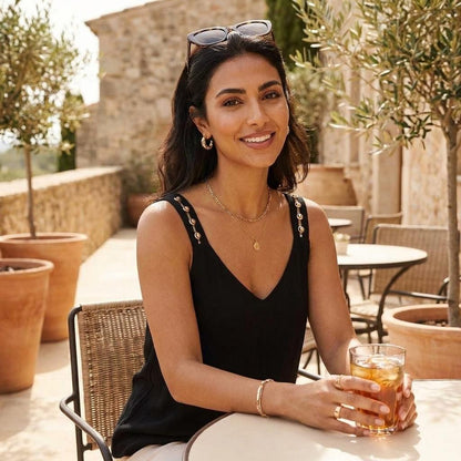 Woman smiling with a drink on a sunny patio.