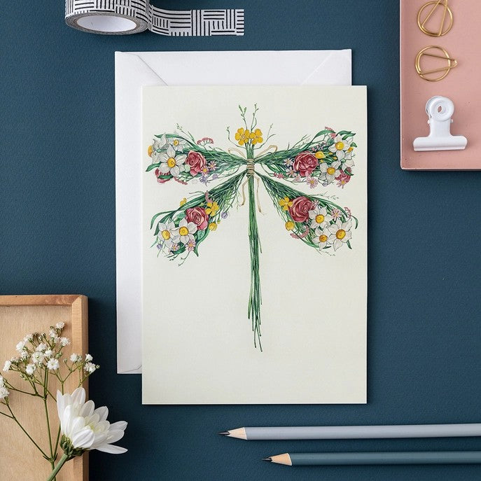 Floral dragonfly card with envelopes, pencils, and decorative items.