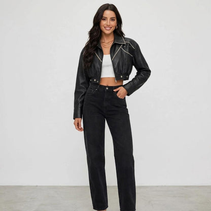 A smiling model wears a cropped black leather jacket, white top, and black jeans.