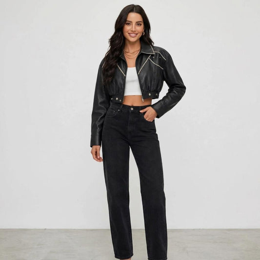 A smiling model wears a cropped black leather jacket, white top, and black jeans.
