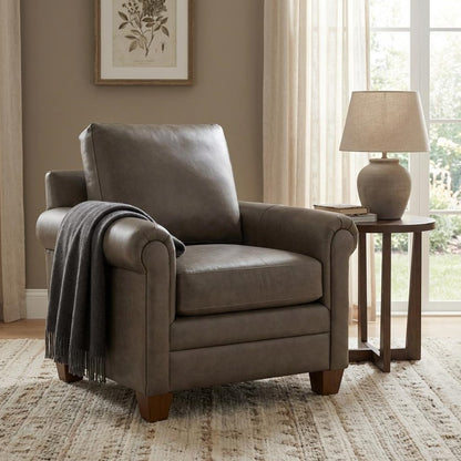 Cozy armchair with a throw, beside a lamp and table, in a sunlit room.