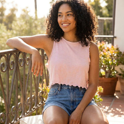Woman smiling on a sunny balcony in casual summer attire.
