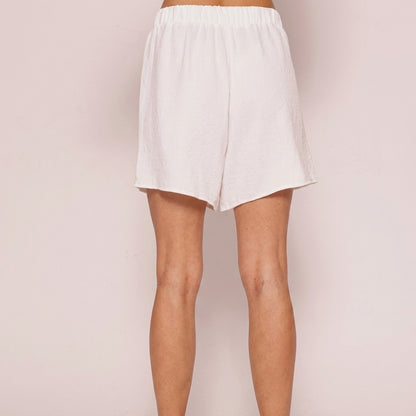 Person wearing white shorts on a neutral background.