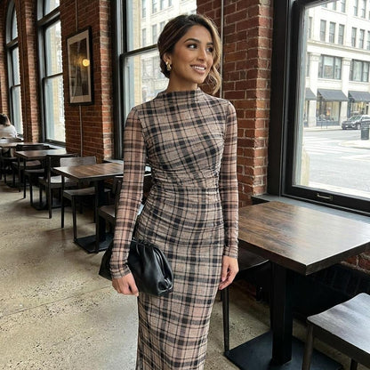 Person in a plaid dress stands in a rustic cafe with brick walls.
