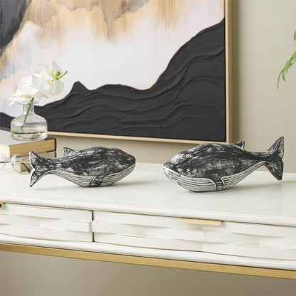 Two decorative whale sculptures on a white shelf.