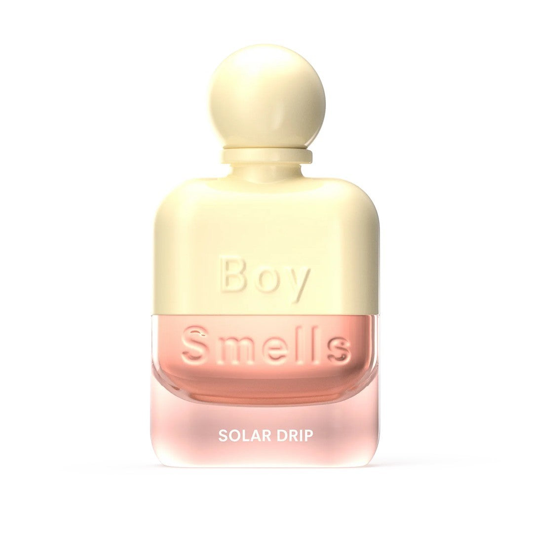 Perfume bottle: "Boy Smells, Solar Drip" in a cream and pink design.