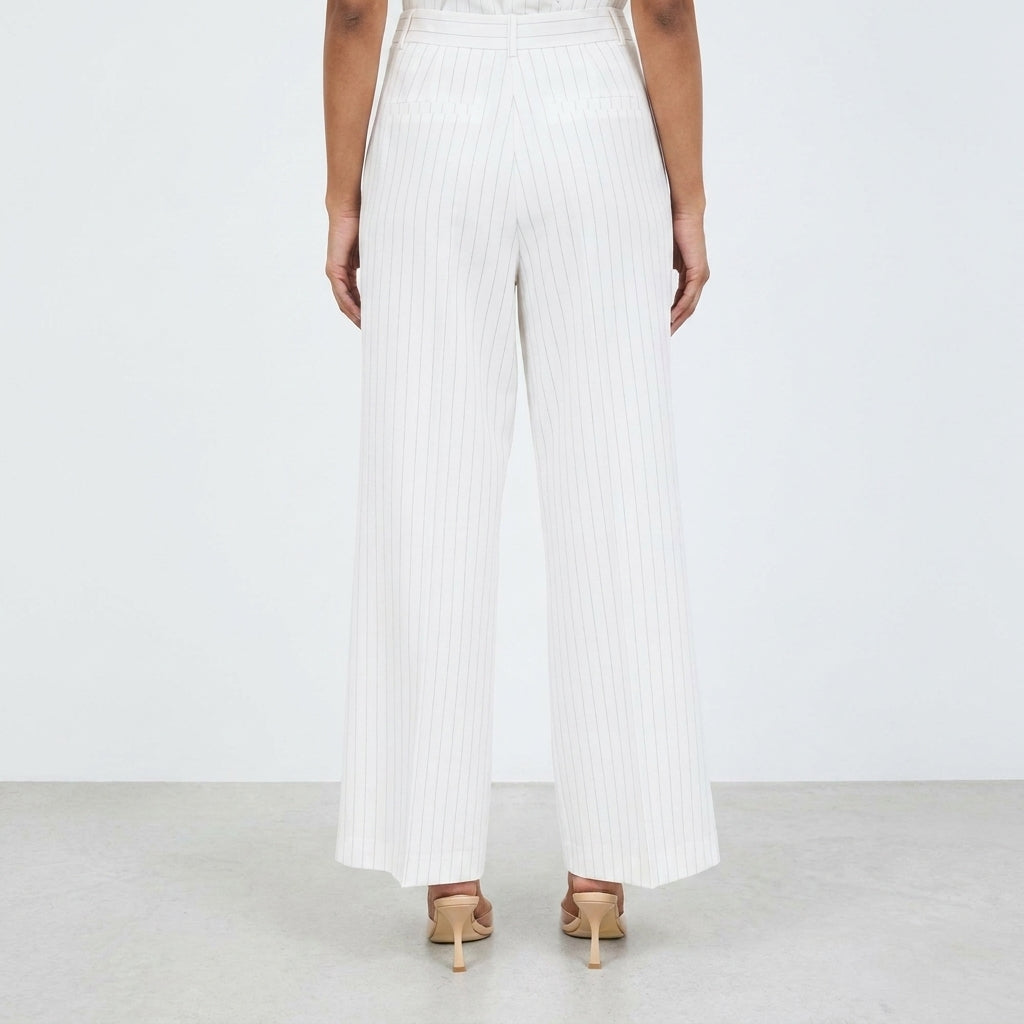 Person in white pinstripe pants and heels, standing on a light floor.