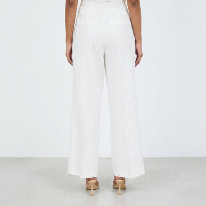 Person in white pinstripe pants and heels, standing on a light floor.