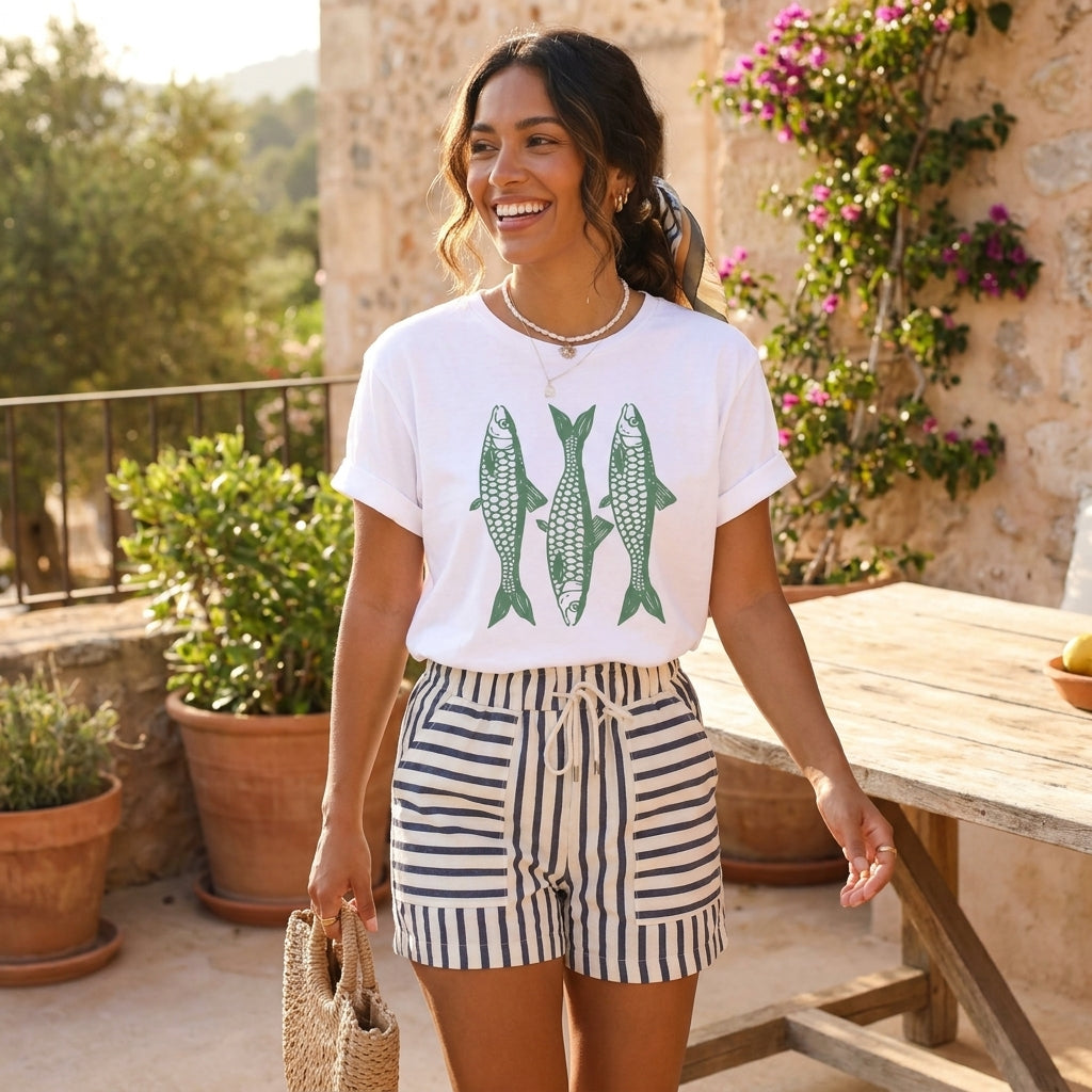Smiling woman in fish print shirt and striped shorts outdoors.