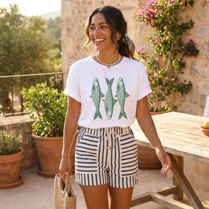 Smiling woman in fish print shirt and striped shorts outdoors.
