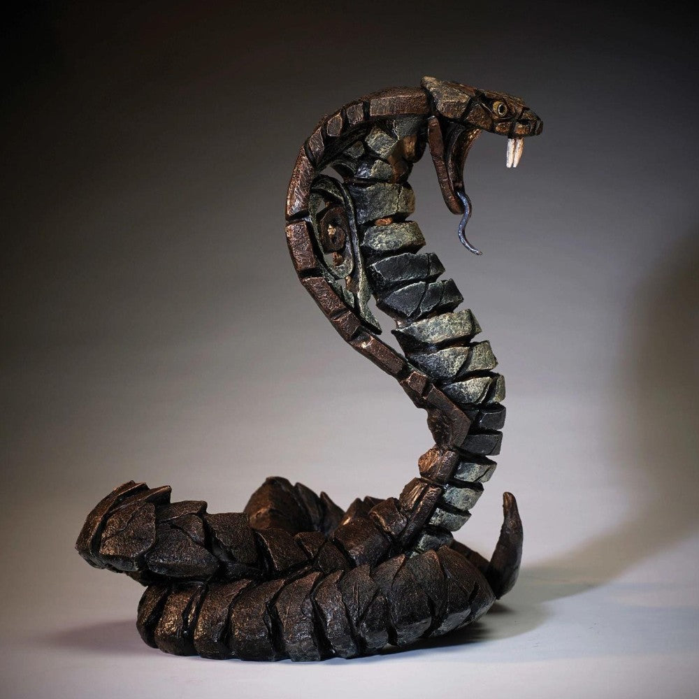A stone-like cobra sculpture with detailed scales and open mouth.