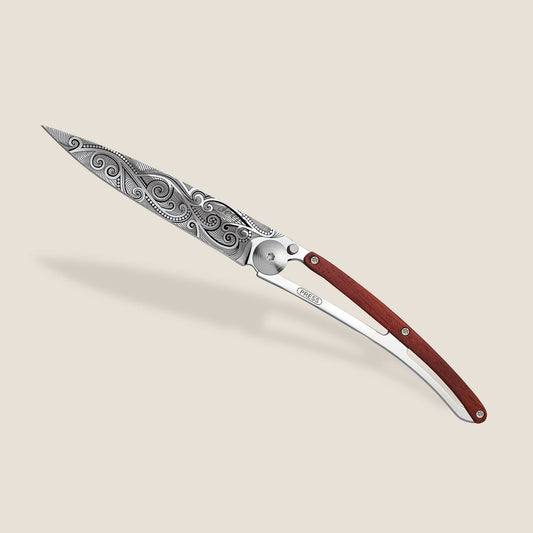Ornate folding knife with a decorative blade and wooden handle.