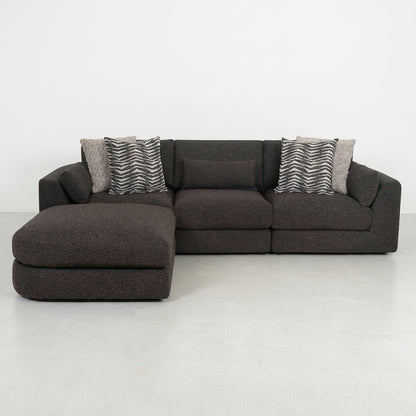 Dark L-shaped sofa with patterned cushions on a light floor.