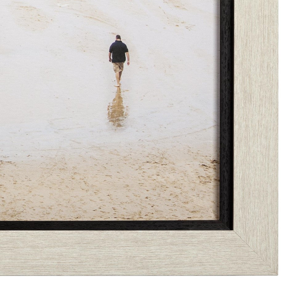 Person walking on a sandy beach, captured from behind.