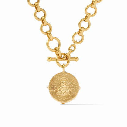 A gold chain necklace with a hammered round pendant and toggle clasp.