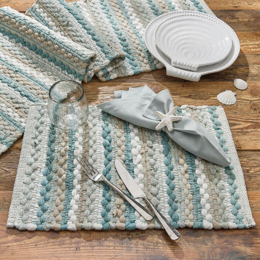 Coastal-themed table setting with striped mats and shell decor.