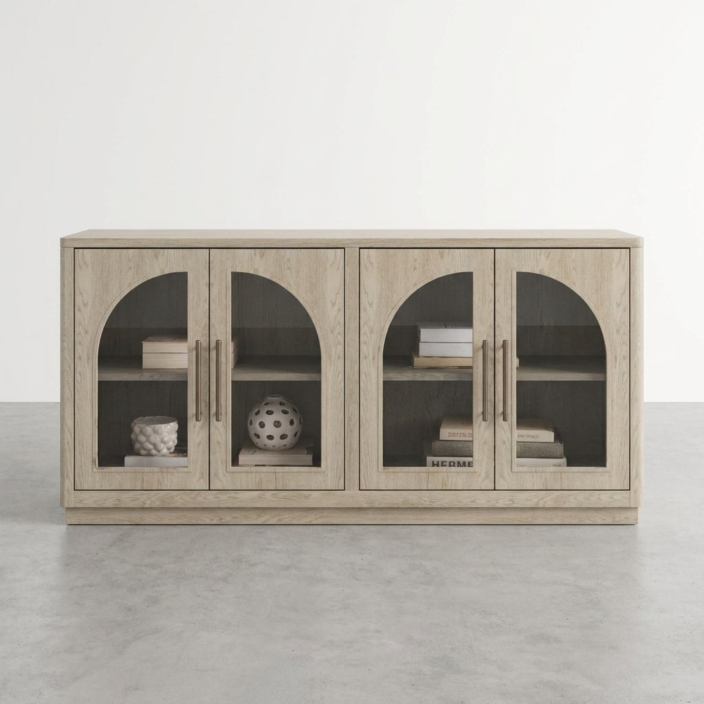 A light wood cabinet with arched glass doors displays books and decorative objects.