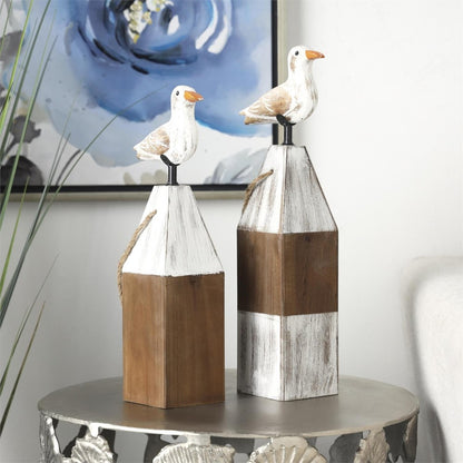 Two wooden seagull sculptures on a decorative table.