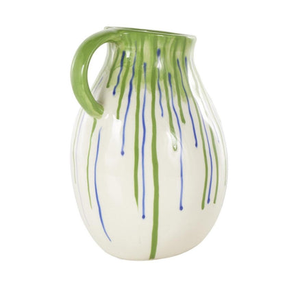 White pitcher with green handle and blue-green drips.