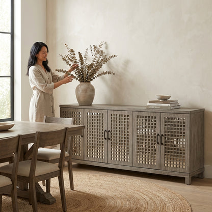 Person arranging vase on minimalist sideboard in a bright, cozy dining room.