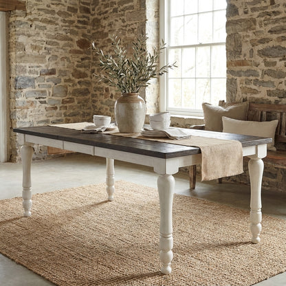 Wooden dining table with dark top and white legs.