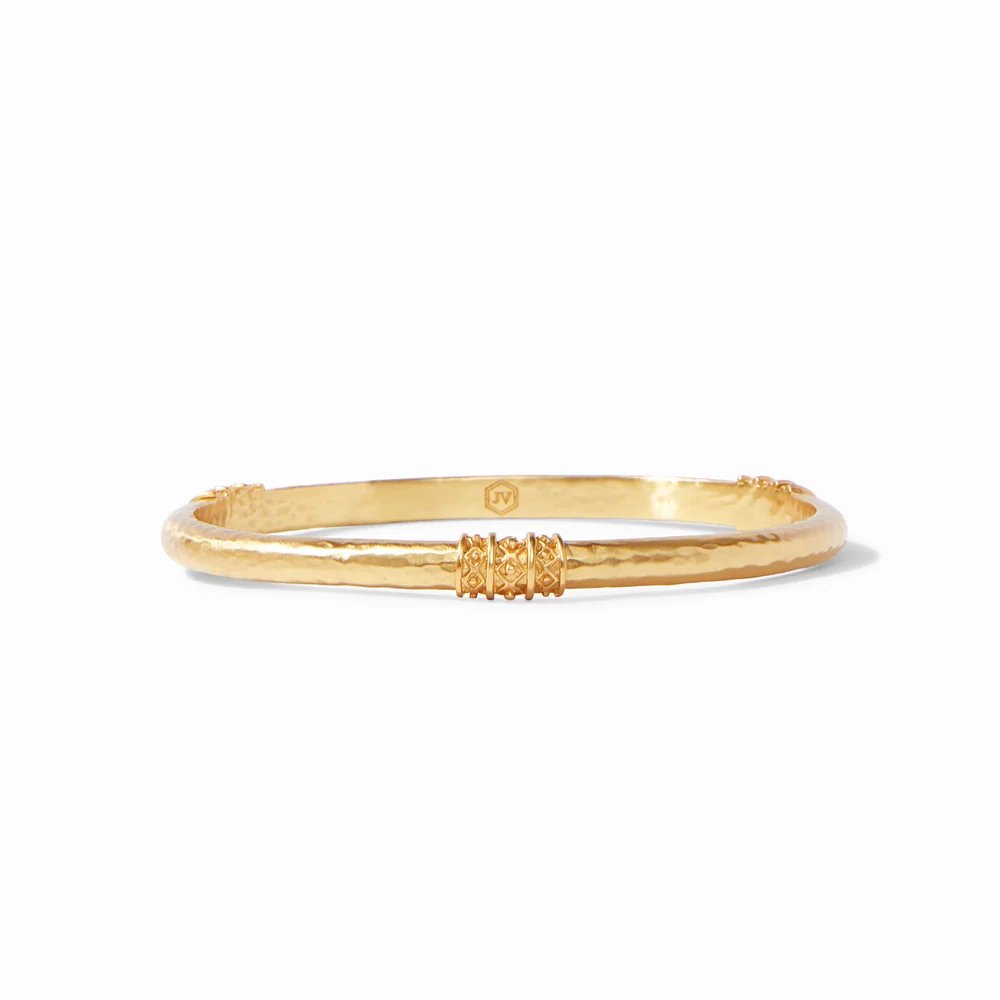 A hammered gold bangle bracelet with decorative engraved accents.